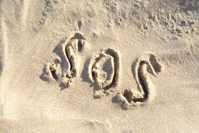 Photo of SOS message written on sandy beach outdoors, top view