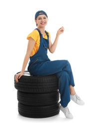 Female mechanic with car tires on white background