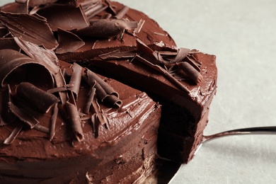 Photo of Tasty homemade chocolate cake and shovel on grey table, closeup