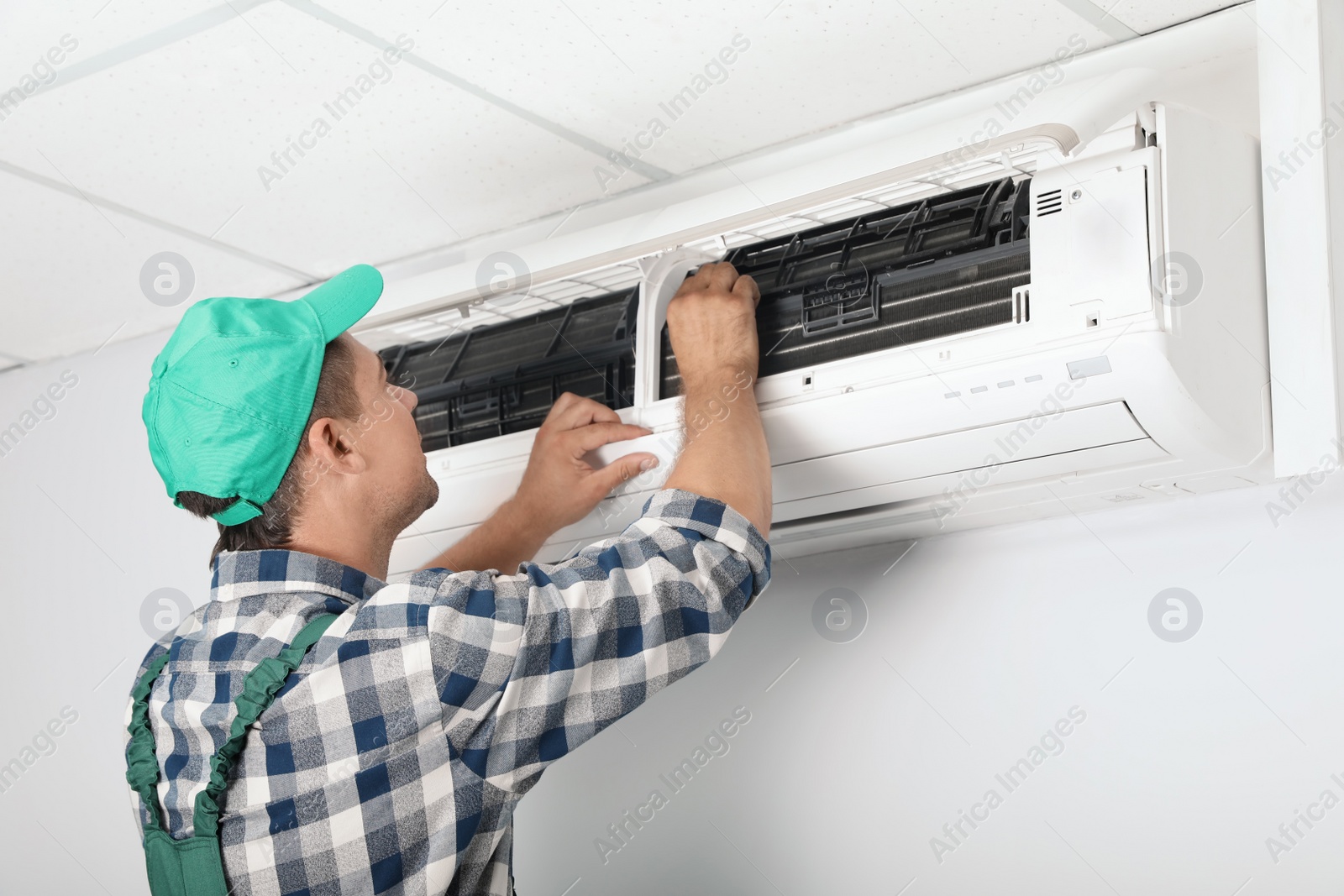 Photo of Male technician cleaning air conditioner indoors