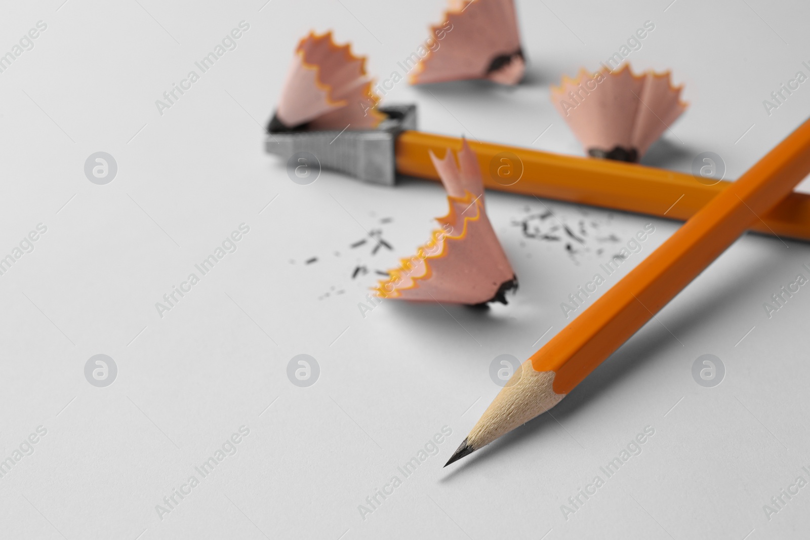 Photo of Graphite pencils, shavings and sharpener on white background, closeup. Space for text