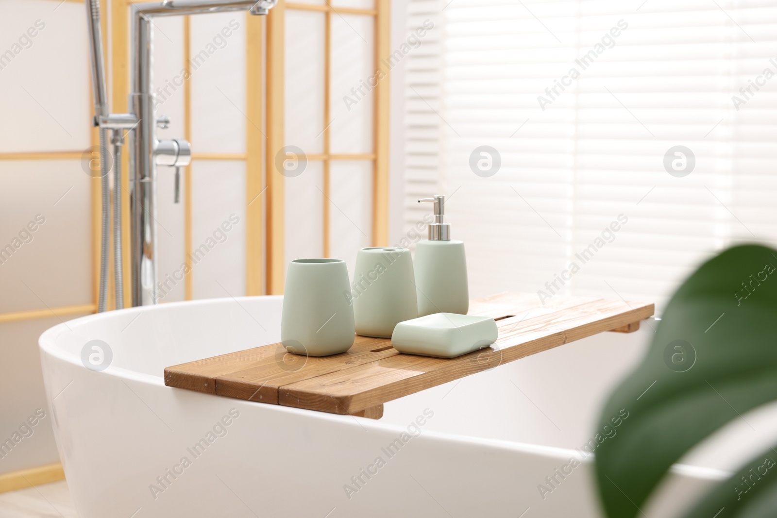 Photo of Set of bath accessories on tub in bathroom