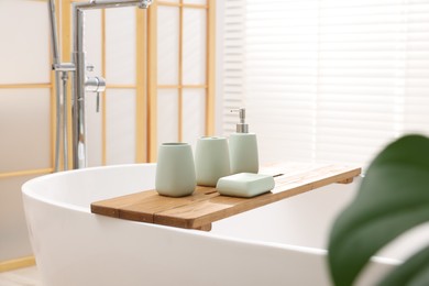 Photo of Set of bath accessories on tub in bathroom