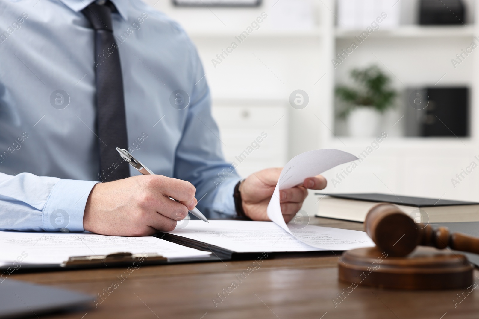 Photo of Lawyer working with documents at wooden table in office, closeup