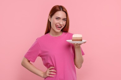 Young woman with piece of tasty cake on pink background