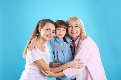 Photo of Beautiful mature woman with daughter and grandchild on color background