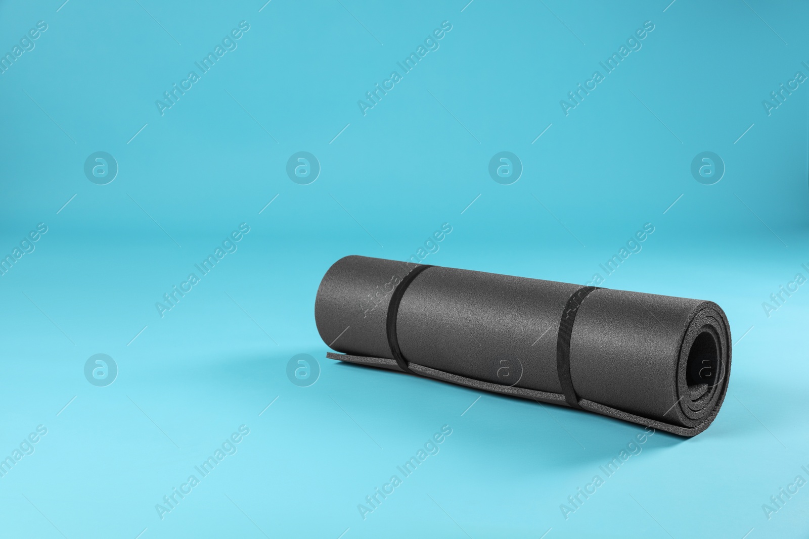 Photo of Grey yoga mat on light blue background. Space for text