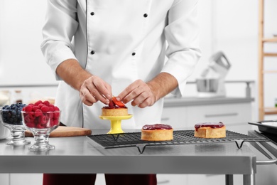 Male pastry chef preparing dessert at table in kitchen, closeup