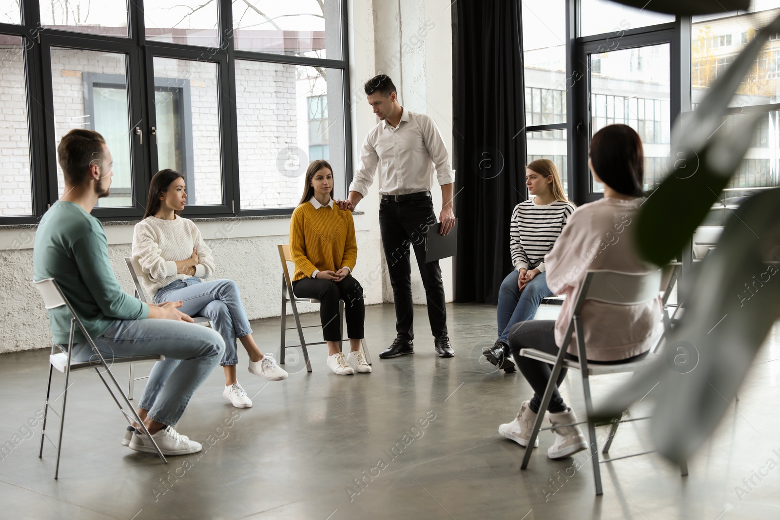 Photo of Psychotherapist working with patients in group therapy session indoors