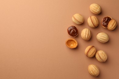 Photo of Homemade walnut shaped cookies with boiled condensed milk on pale brown background, flat lay. Space for text