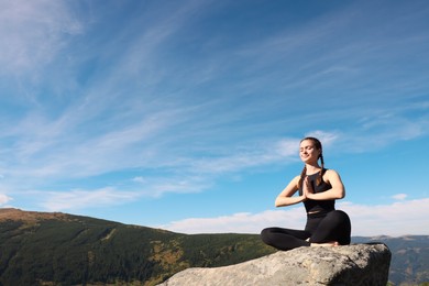 Photo of Young woman practicing outdoor yoga in mountains, space for text. Fitness lifestyle