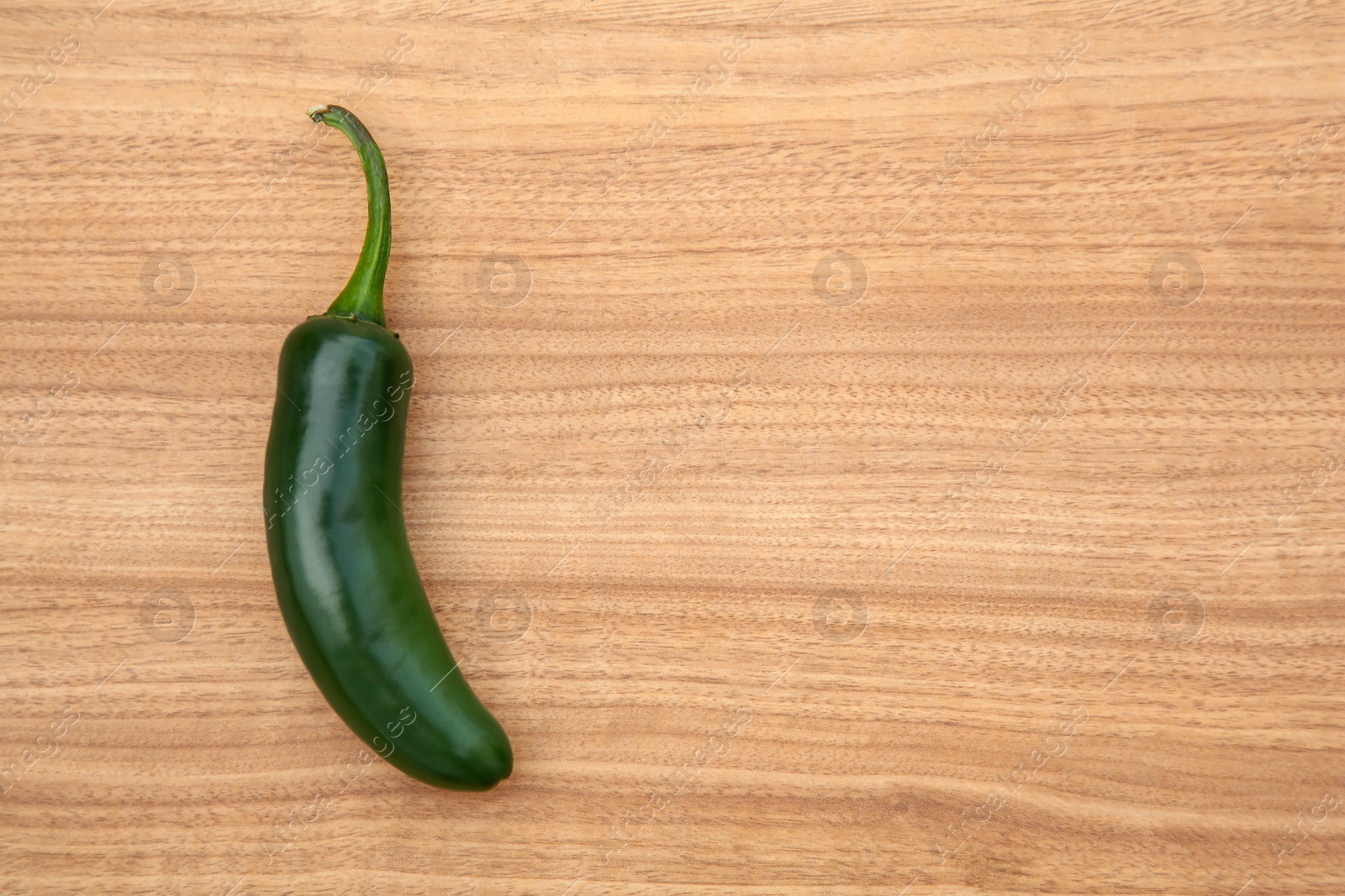 Photo of Fresh green jalapeno pepper on wooden table, top view. Space for text