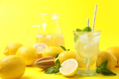 Photo of Natural freshly made lemonade with squeezer on yellow background. Summer refreshing drink