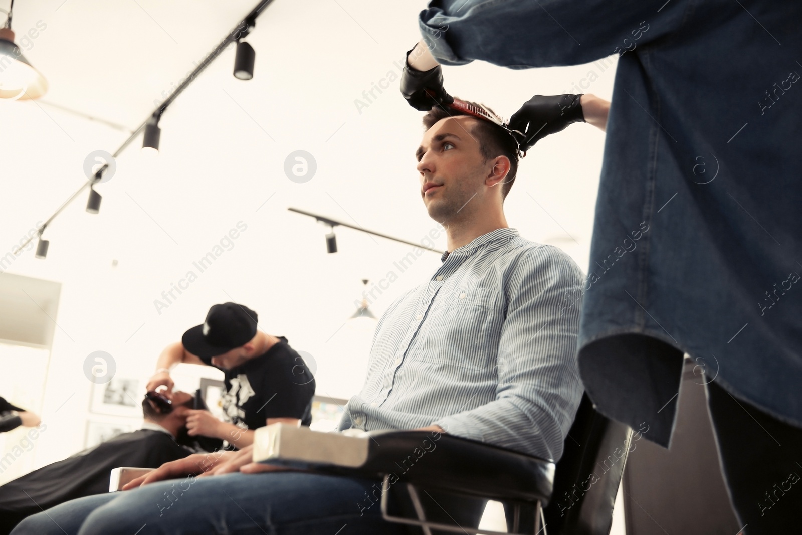 Photo of Professional barber working with client in hairdressing salon. Hipster fashion