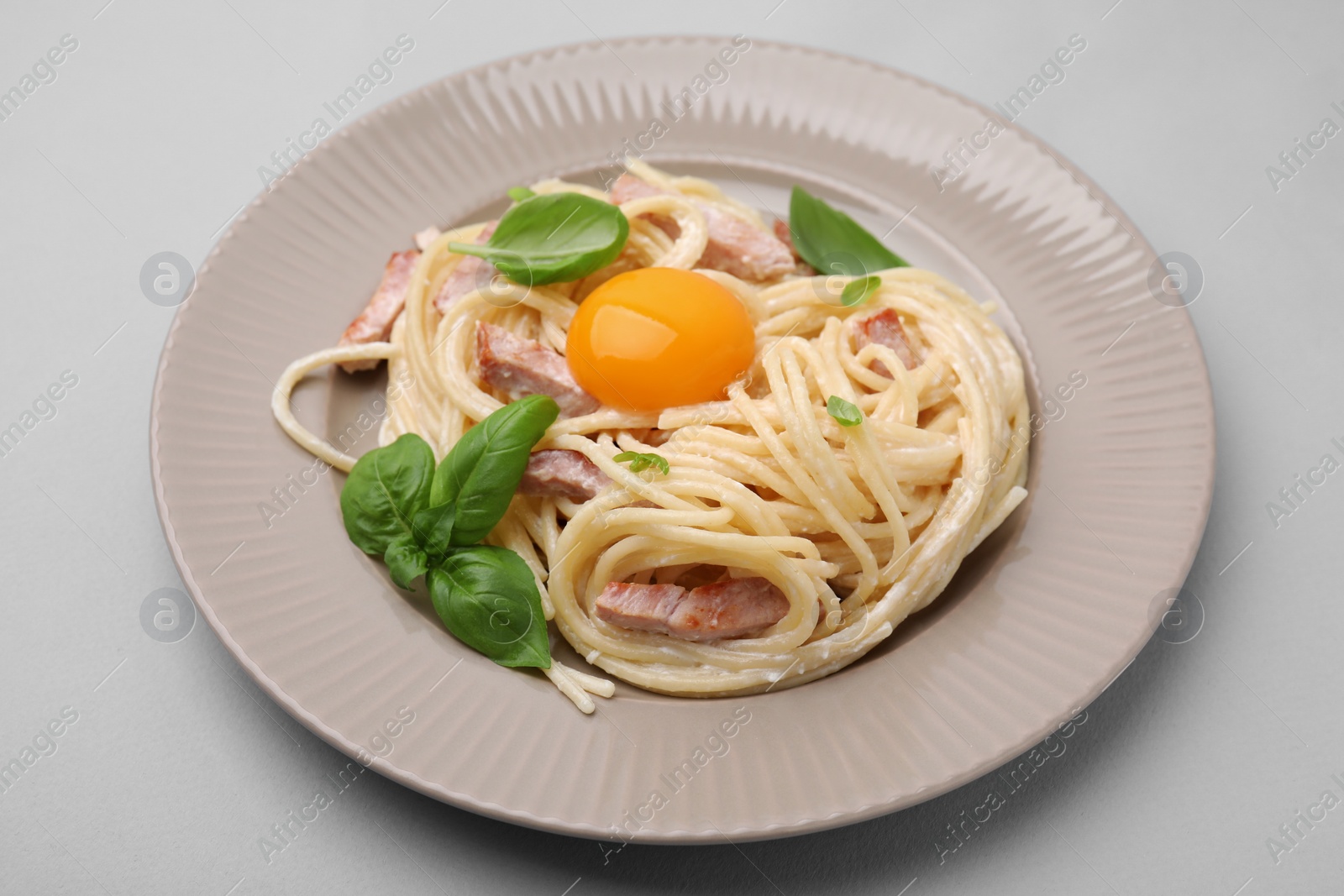 Photo of Delicious pasta Carbonara with egg yolk on light blue background, closeup