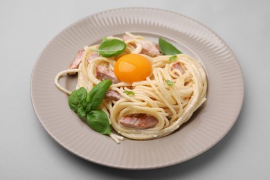 Delicious pasta Carbonara with egg yolk on light blue background, closeup