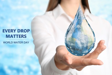 Image of World Water Day. Woman holding icon of drop with Earth image inside on blurred background, closeup