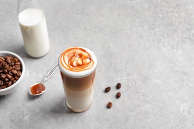 Photo of Glass with delicious caramel latte on table