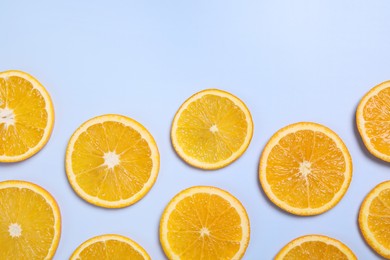Photo of Slices of juicy orange on light blue background, flat lay. Space for text