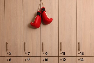 Photo of Red boxing gloves hanging on locker door in changing room