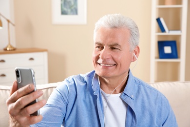 Photo of Mature man using video chat on mobile phone at home