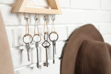Wooden key holder on white brick wall indoors, closeup
