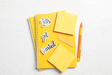 Photo of Sheets of paper with phrase Let's Get Started and stationery on white table, flat lay