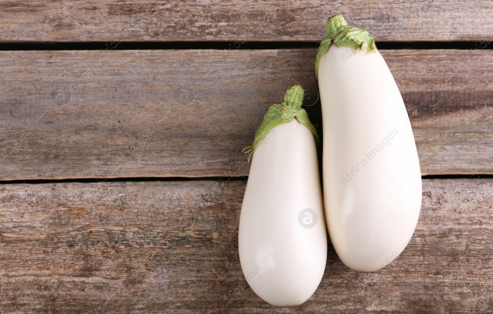 Photo of Fresh white eggplants on wooden table, flat lay. Space for text