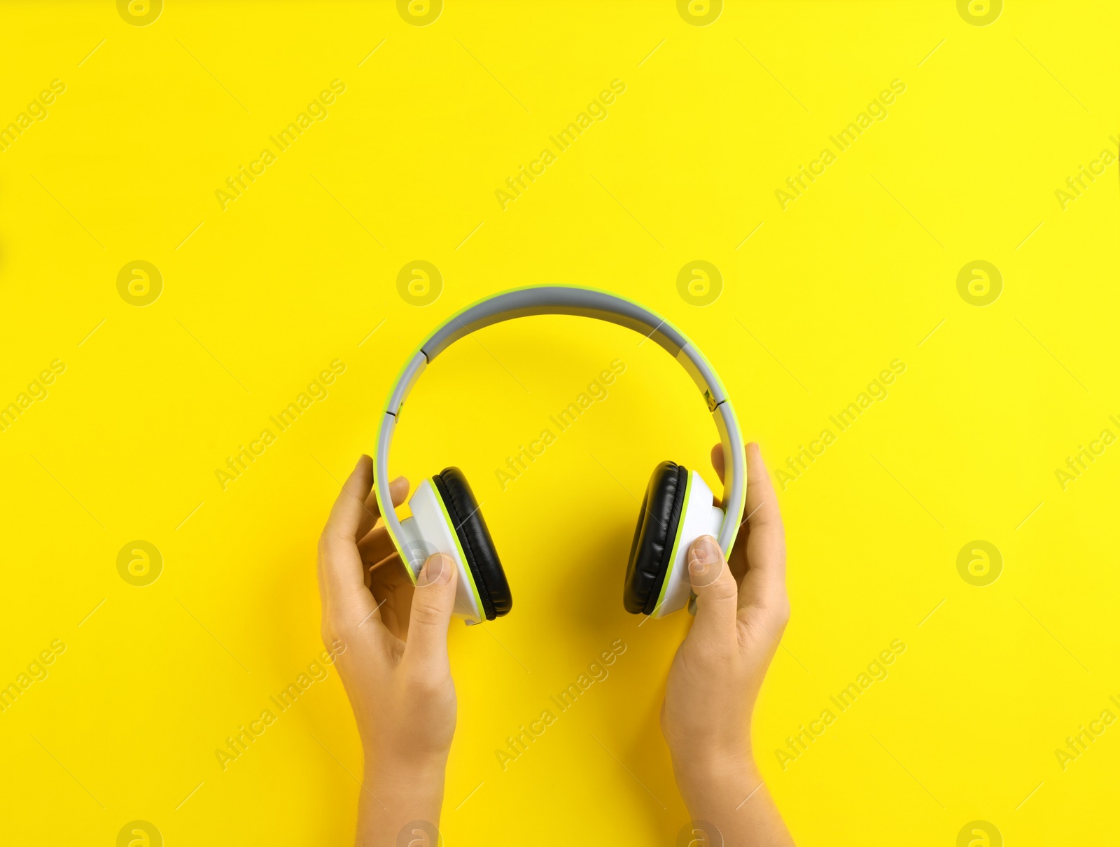 Photo of Woman holding headphones on color background, top view