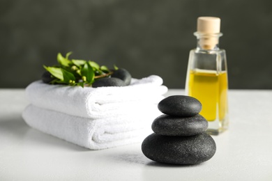 Spa stones, towels and oil on white table