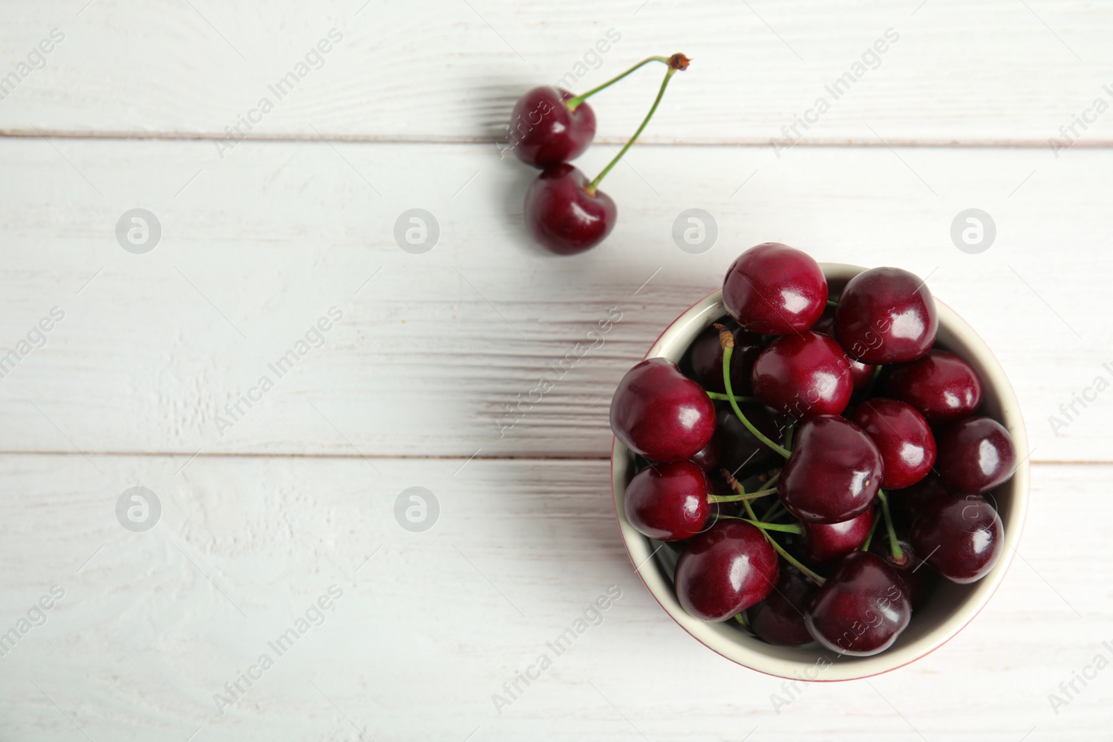 Photo of Bowl with sweet red cherries on wooden table, top view