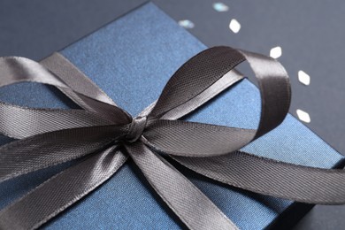 Beautiful gift box with bow on black background, closeup view