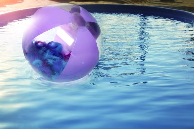 Image of Inflatable beach ball floating in swimming pool 