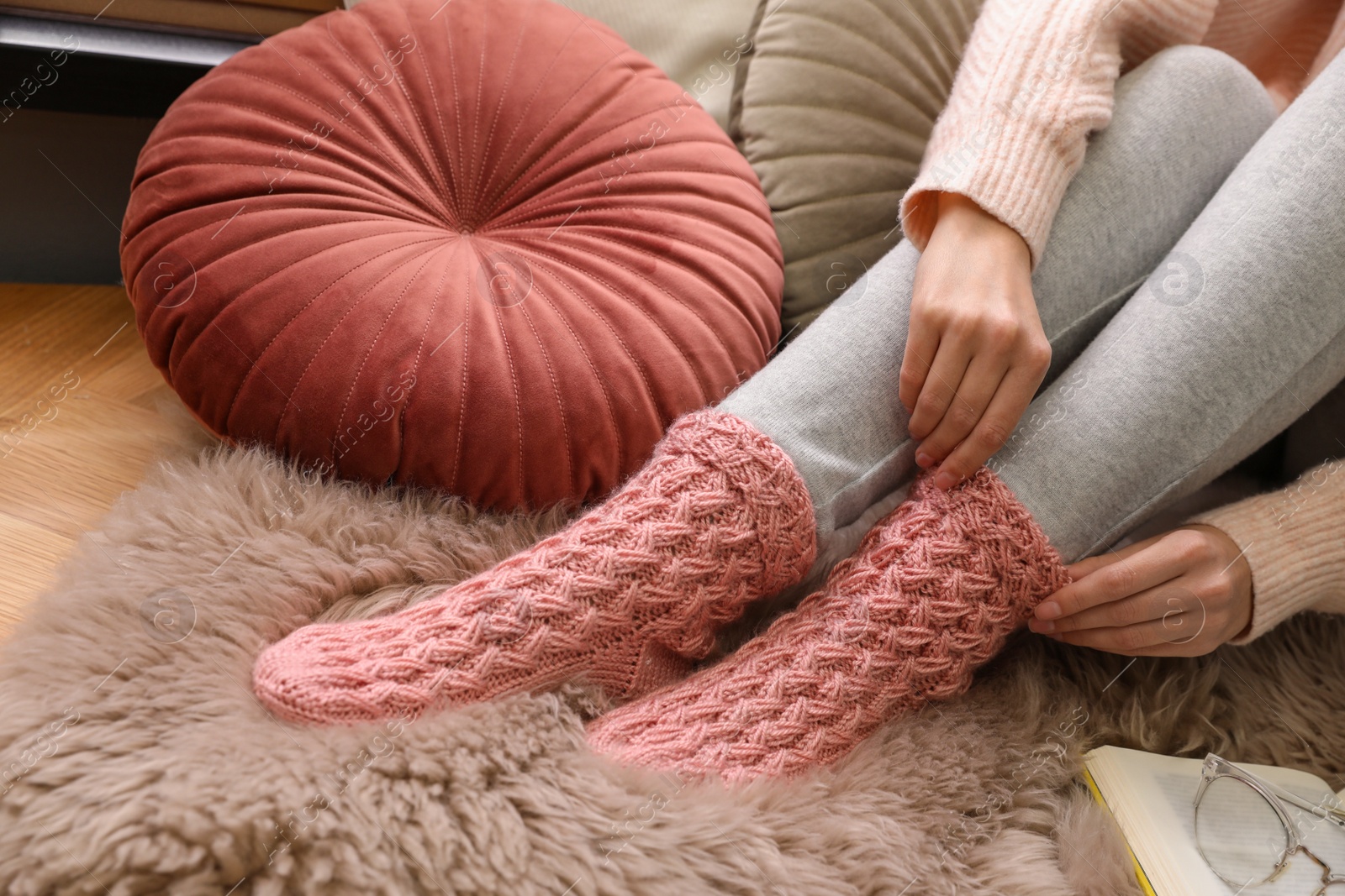 Photo of Woman wearing warm knitted socks on floor at home, closeup