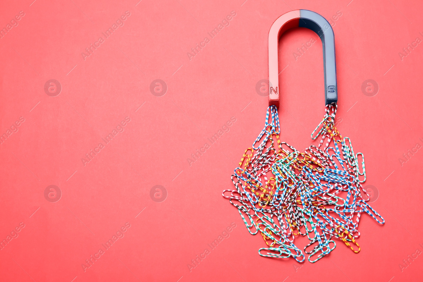 Photo of Magnet attracting paper clips on color background, space for text