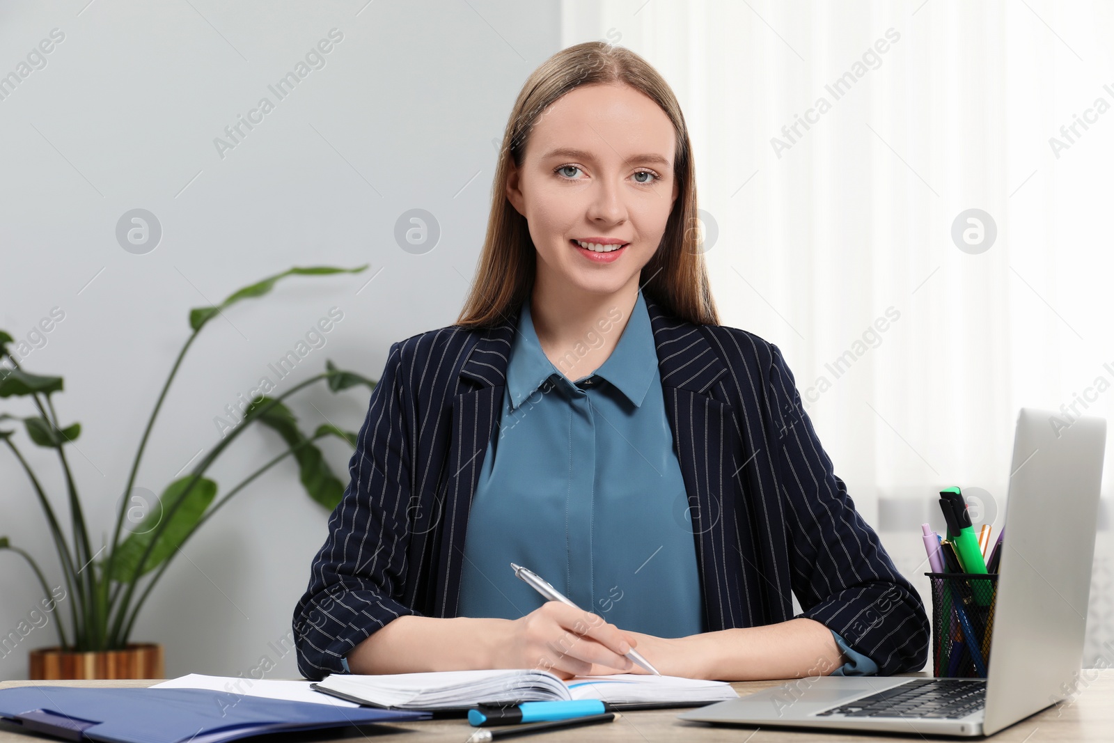 Photo of Woman taking notes at table in office