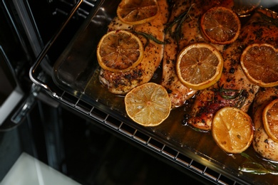 Baking dish with delicious lemon chicken in oven, closeup view
