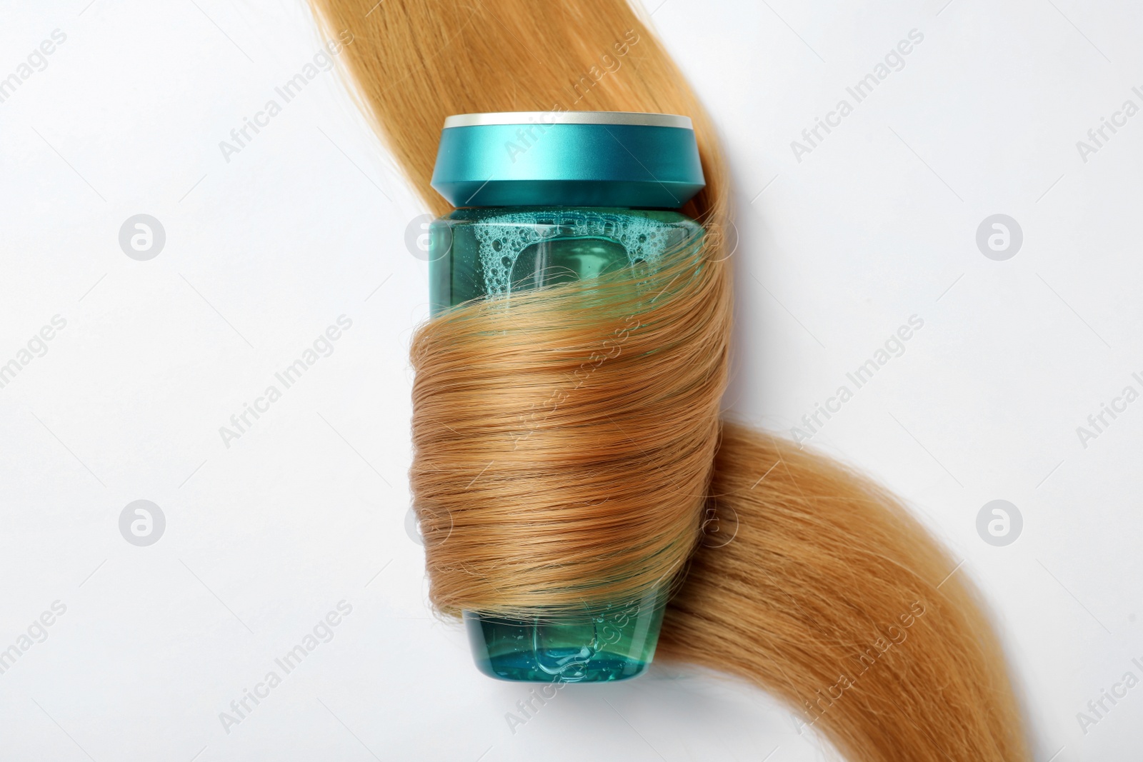 Photo of Bottle wrapped in lock of hair on white background, top view. Natural cosmetic product