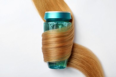 Photo of Bottle wrapped in lock of hair on white background, top view. Natural cosmetic product