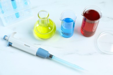 Photo of Laboratory analysis. Micropipette, petri dish and other glassware on white marble table