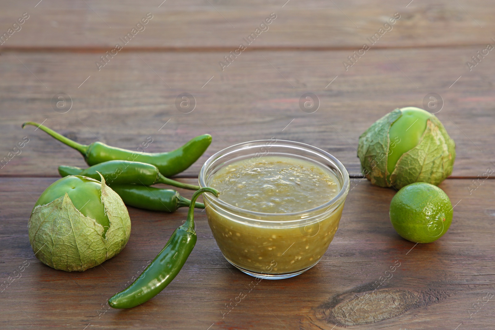 Photo of Tasty salsa sauce and ingredients on wooden table, closeup