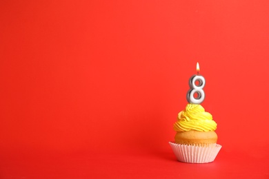 Photo of Birthday cupcake with number eight candle on red background, space for text