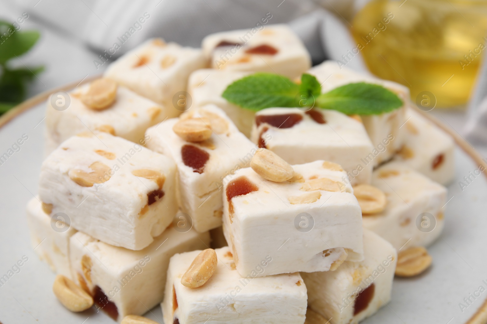 Photo of Pieces of delicious nutty nougat on plate, closeup