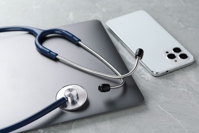 Modern electronic devices and stethoscope on grey table