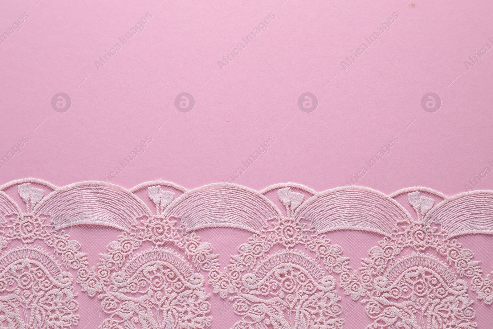 Photo of White lace on pink background, top view. Space for text