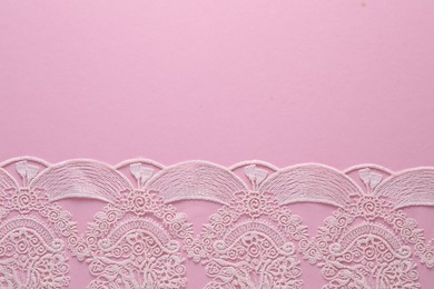 Photo of White lace on pink background, top view. Space for text