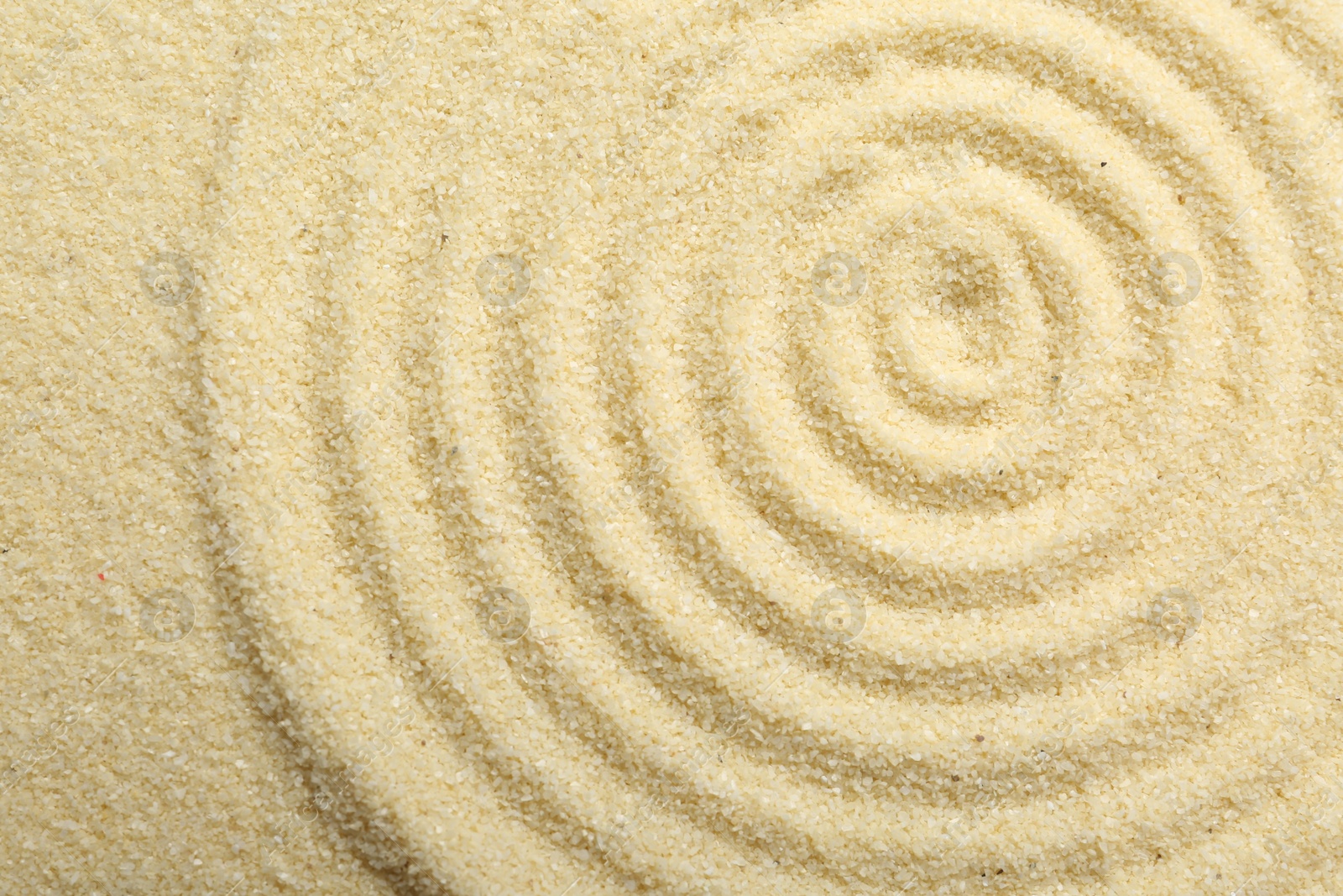 Photo of Zen rock garden. Circle pattern on beige sand, top view