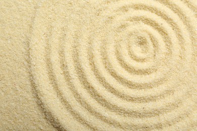 Photo of Zen rock garden. Circle pattern on beige sand, top view