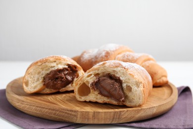Photo of Fresh croissants with chocolate on wooden plate. Space for text