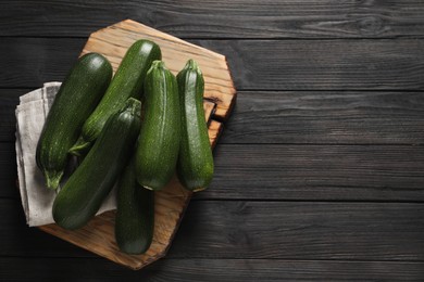 Raw ripe zucchinis on black wooden table, top view. Space for text